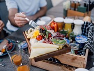 Eine Wurst- und Käseplatte und eine Kiste mit Joghurt, Säften und anderen Spezialitäten.