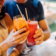 Eine Frau und ein Mann stoßen mit Cocktails an.