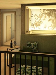 Ein Balkon mit einer Sitzbank und einem Beistelltisch mit einer Flasche Wein und zwei Gläsern. 