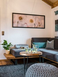 Eine Couch & ein Beistelltisch mit einer Karaffe Zitronenwasser darauf im Chalet.