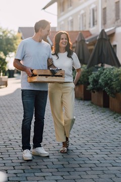 Ein Mann träge eine Kiste mit Lebensmitteln, eine Frau hält ihn am Arm.