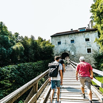 Eine Gruppe geht über eine Holzbrücke zur Burg Tittmoning.