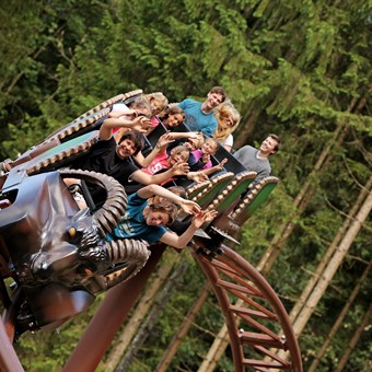Menschen in einer Achterbahn mit Steinbock-Kopf.