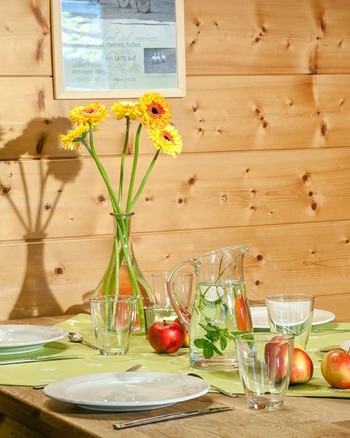 Gedeckter Tisch mit einer Blumenvase und Äpfeln als Dekoration.