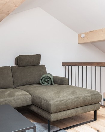 Gemütliches Sofa auf der Galerie mit Dachschräge und Couchtisch mit Trauben und Wein.