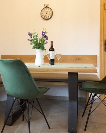 Essbereich mit einer Blumenvase, einer Wienflasche und Weingläsern auf dem Tisch.