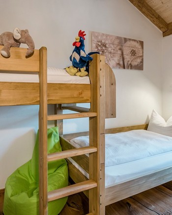 Stockbett und ein Einzelbett mit Stofftieren auf allen Betten im Kinderzimmer des Chalets.