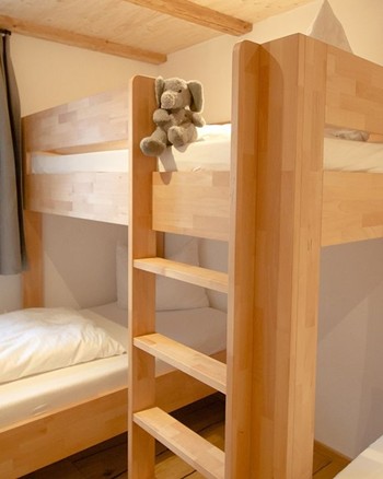 Ein Stockbett mit einem Stofftier auf dem oberen Bett und ein Einzelbett im Schlafzimmer der Ferienwohnung.