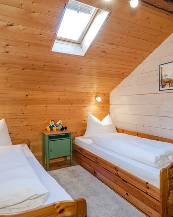 Kinderzimmer in der Ferienwohnung mit zwei Einzelbetten und Stofftieren auf den Möbeln.