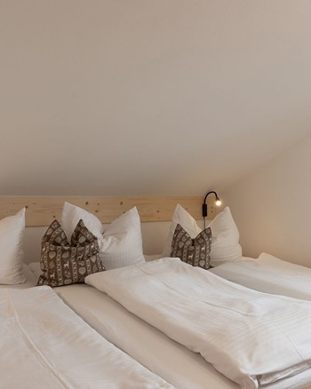 Großes Bett in einem kleinen Raum mit Dachschräge.