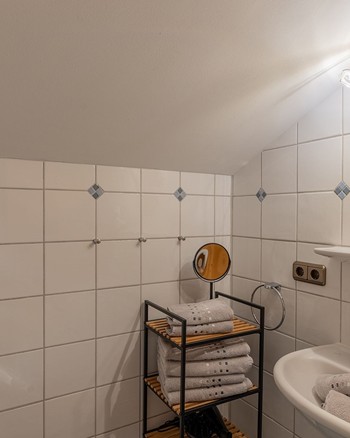 Waschbecken, Spiegel und ein Regal mit Handtüchern im Badezimmer der Ferienwohnung.