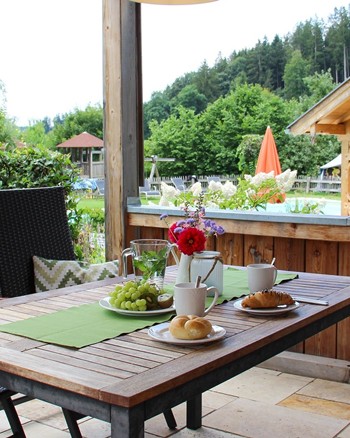 Sitzgarnitur auf der Terrasse der Ferienwohnung mit Obst und Gebäck auf dem Tisch.