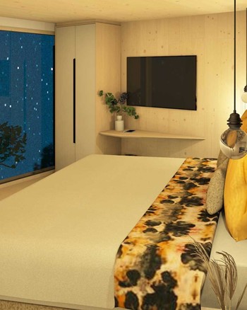 Schlafzimmer mit Doppelbett und freistehender Badewanne vor einem großen Fenster.