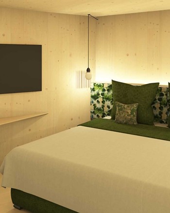 Schlafzimmer mit Fernseher und Doppelbett mit grünen Farbakzenten.