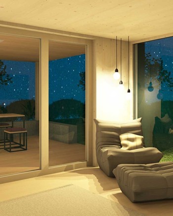 Gemütlicher Sessel im Wohnzimmer mit Fensterfronten zur Terrasse und zum Garten auf beiden Seiten.