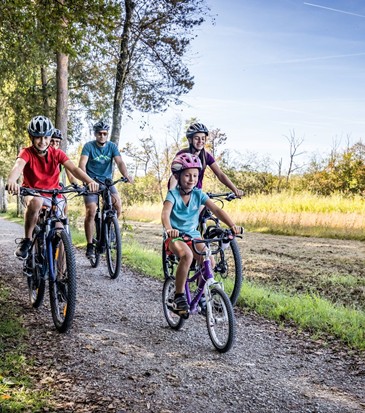Eine Familie fährt mit Fahrrädern einen Pfad entlang.
