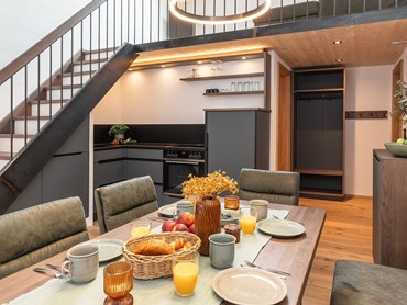 Kochnische und Essbereich mit gedecktem Frühstückstisch und Treppe zum zweiten Stock.