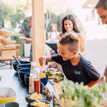 Ein Kind belegt sich einen Burger am Buffet.
