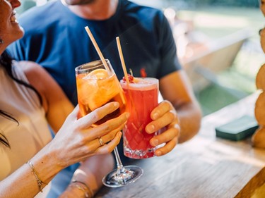 Eine Frau und ein Mann stoßen mit Cocktails an.