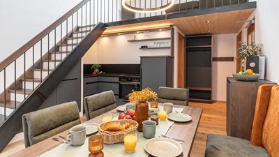 Kochnische und Essbereich mit gedecktem Frühstückstisch und Treppe zum zweiten Stock.