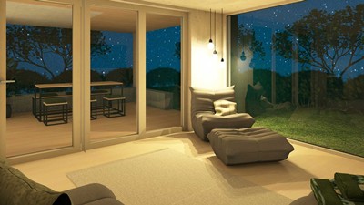 Gemütlicher Sessel im Wohnzimmer mit Fensterfronten zur Terrasse und zum Garten auf beiden Seiten.