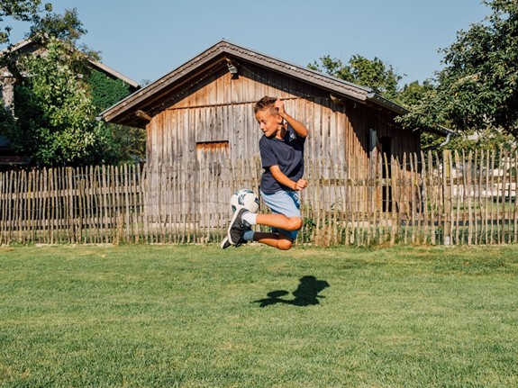 Ein Kind kickt einen Fußball mit der Ferse in die Luft.