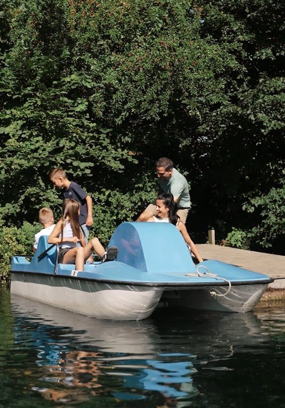 Eine Familie steigt in ein Tretboot ein, das am Steg anliegt.