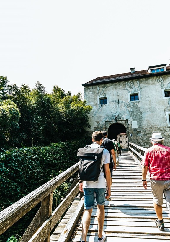 Eine Gruppe geht über eine Holzbrücke zur Burg Tittmoning.