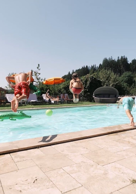 Kinder springen in den Outdoor Pool.